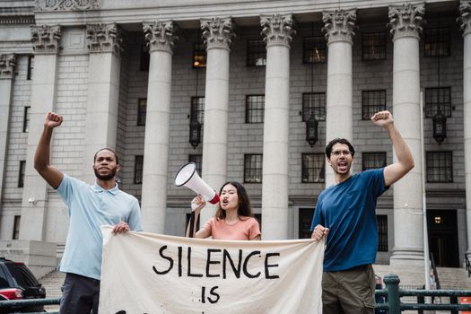 Groupe de manifestants devant un bâtiment, brandissant une banderole et un mégaphone pour une marche féministe.