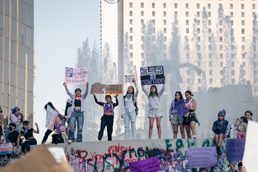 Groupe de femmes sur une scène lors d'une marche féministe, brandissant des pancartes et exprimant leur solidarité.