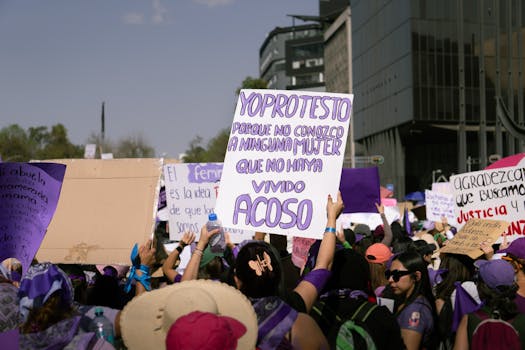 Manifestation féministe avec des pancartes, des banderoles violettes et des participants exprimant leur solidarité.