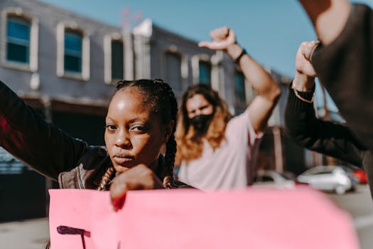 Femme levant le poing avec un panneau lors d'une marche féministe, entourée de manifestants en arrière-plan.